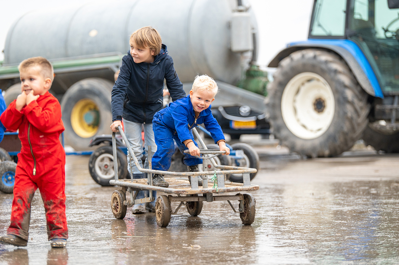 Uitje met kinderen in Noord-Holland. kinderen met skelter op pruttige ondergrond, op achtergrond landbouwvoertuigen