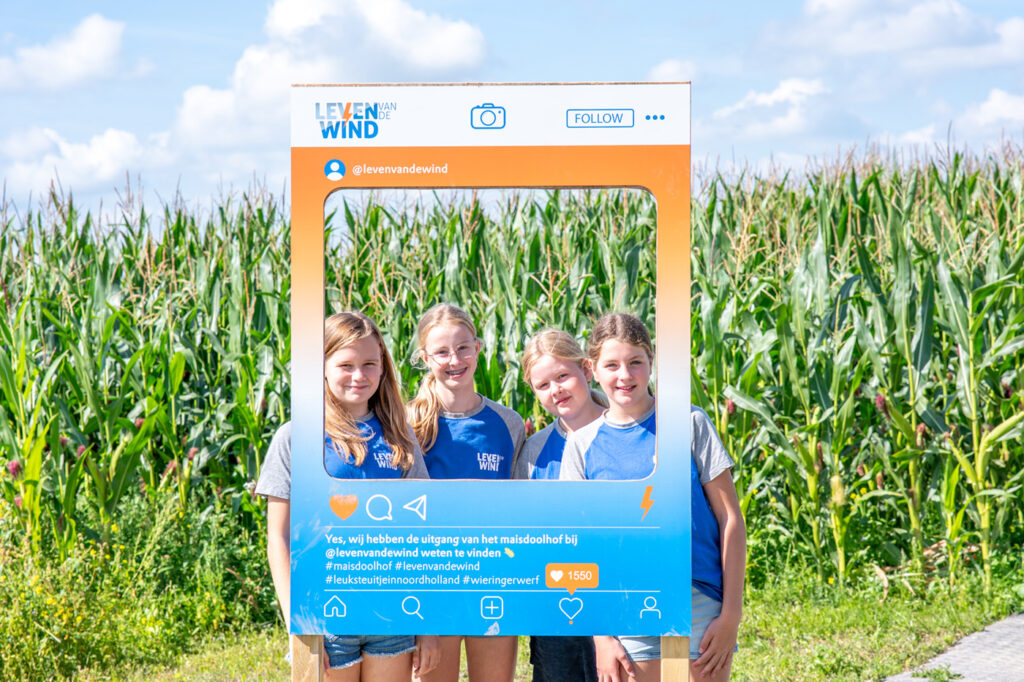Maisdoolhof Wieringerwerf - 4 meiden in een fotobord gepositioneerd voor een maisveld